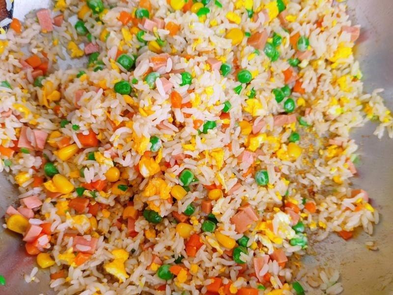Stir-frying crispy rice with ingredients for homemade Yangzhou Fried Rice